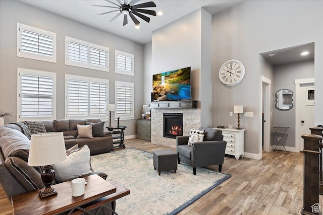 3851 N 425 E, North Ogden, UT 84414 - living room with ceiling fan, light hardwood / wood-style floors, a stone fireplace, and a high ceiling