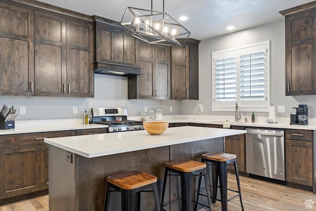 3851 N 425 E, North Ogden, UT 84414 - kitchen with hanging light fixtures, stainless steel appliances, light hardwood / wood-style floors, a textured ceiling, and a kitchen island