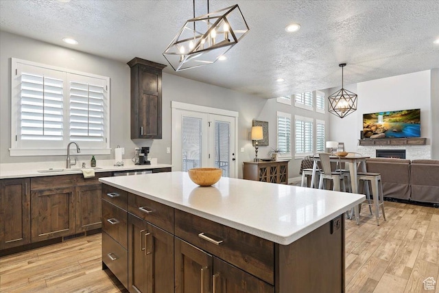 3851 N 425 E, North Ogden, UT 84414 - kitchen with a center island, a fireplace, light hardwood / wood-style floors, and a textured ceiling