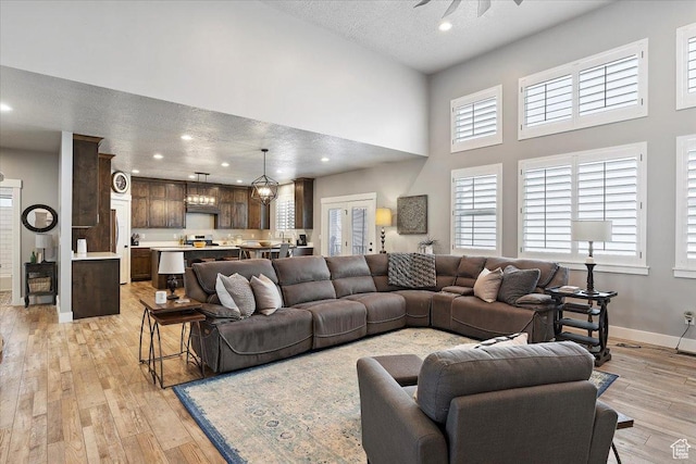 3851 N 425 E, North Ogden, UT 84414 - living room featuring ceiling fan with notable chandelier, light wood-type flooring, a textured ceiling, and a high ceiling