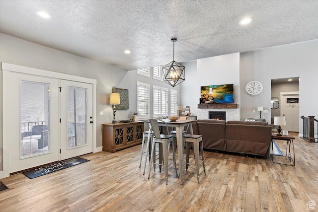 3851 N 425 E, North Ogden, UT 84414 - dining area featuring a notable chandelier, light hardwood / wood-style floors, a stone fireplace, and a textured ceiling