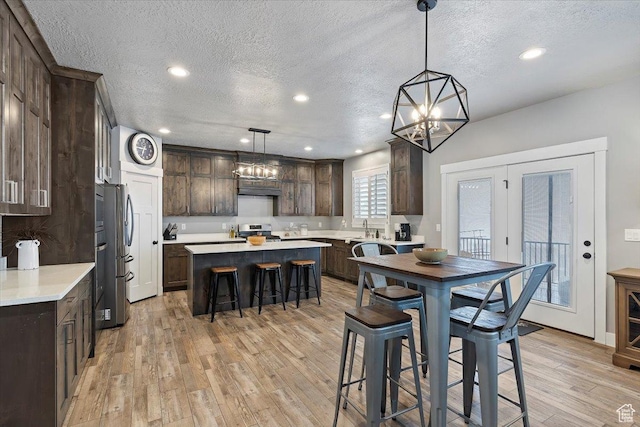 3851 N 425 E, North Ogden, UT 84414 - kitchen with light wood-type flooring, dark brown cabinetry, stainless steel appliances, pendant lighting, and a kitchen island