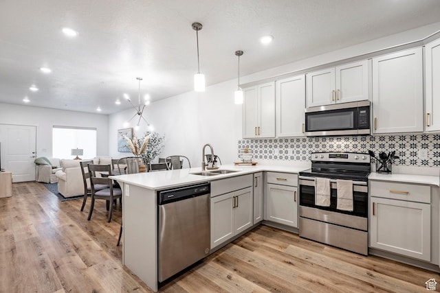 kitchen with decorative backsplash, a peninsula, a sink, and appliances with stainless steel finishes