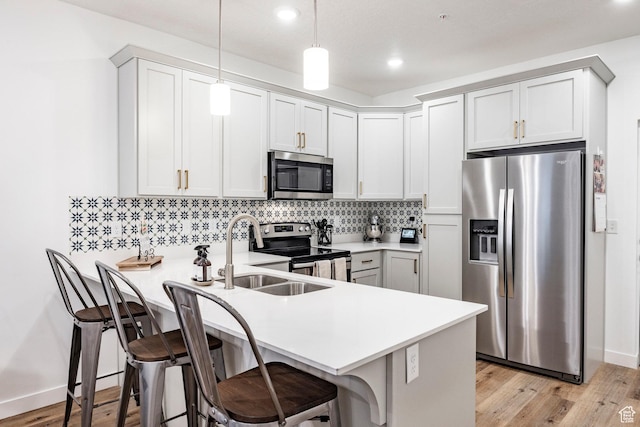 kitchen with stainless steel appliances, light countertops, backsplash, a peninsula, and a kitchen bar