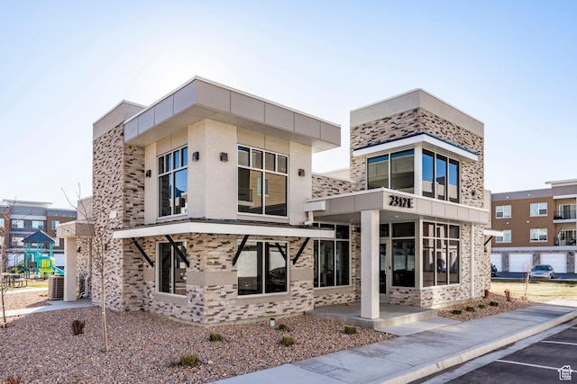 view of property featuring central air condition unit and uncovered parking