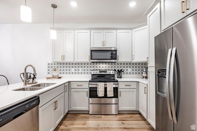 kitchen with light countertops, stainless steel appliances, light wood-type flooring, and a sink