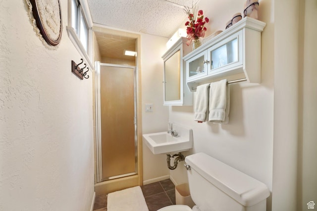 bathroom featuring tile patterned floors, a sink, toilet, baseboards, and a shower stall