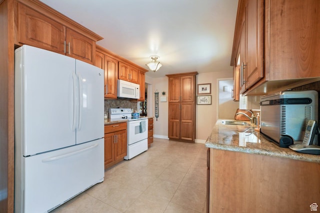 kitchen featuring decorative backsplash, brown cabinets, a sink, and white appliances