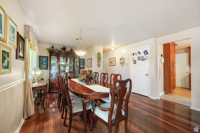 dining space with dark wood finished floors and baseboards