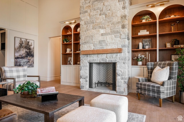 6736 E Via Cortina, Huntsville, UT 84317 - living room with built in shelves, a stone fireplace, light wood-type flooring, and a towering ceiling