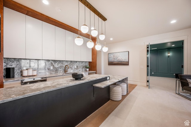 6736 E Via Cortina, Huntsville, UT 84317 - kitchen featuring light stone countertops, backsplash, decorative light fixtures, light hardwood / wood-style flooring, and white cabinets