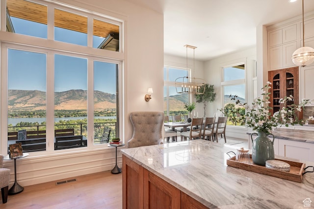 6736 E Via Cortina, Huntsville, UT 84317 - kitchen with pendant lighting, a water and mountain view, an inviting chandelier, light hardwood / wood-style flooring, and light stone counters