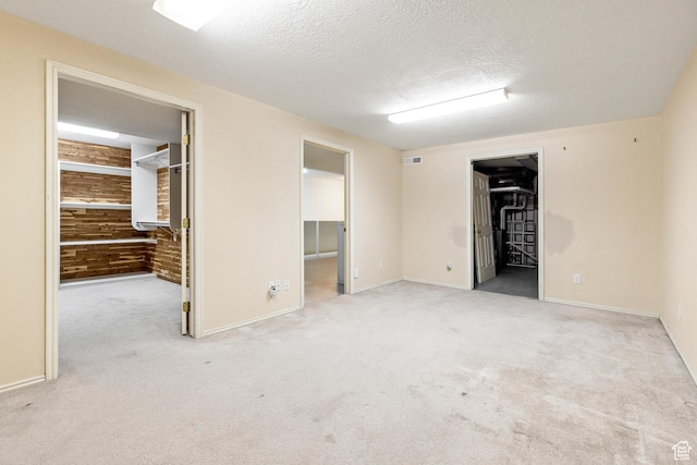carpeted spare room with wooden walls and a textured ceiling