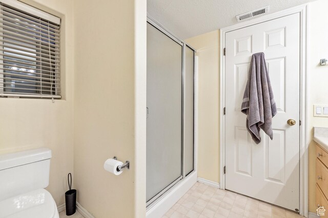 bathroom with toilet, vanity, a textured ceiling, and walk in shower