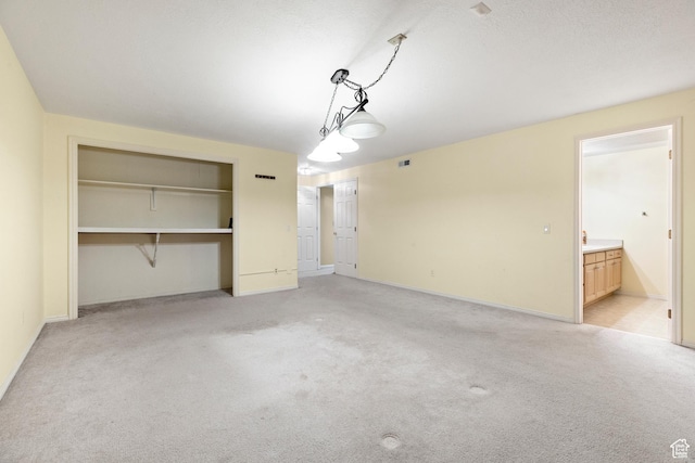 unfurnished bedroom with ensuite bath and light colored carpet
