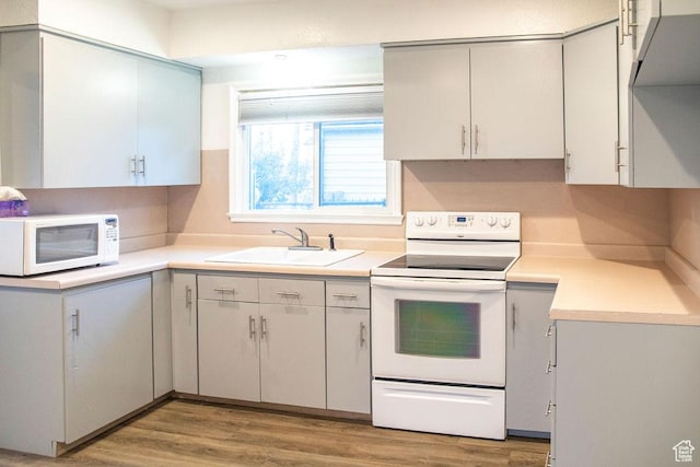 kitchen featuring sink, white appliances, and light hardwood / wood-style flooring