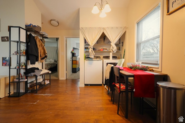 dining room with wood-type flooring, an inviting chandelier, and washer and clothes dryer