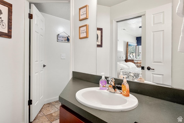 ensuite bathroom with vanity, stone finish flooring, and baseboards