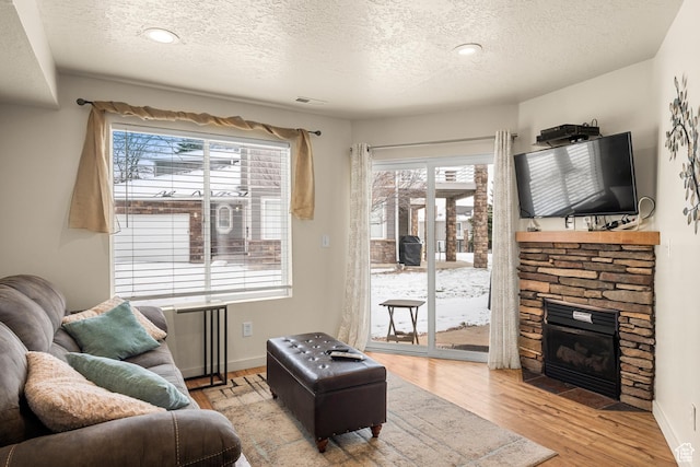 living area featuring a textured ceiling, healthy amount of natural light, wood finished floors, a fireplace, and radiator