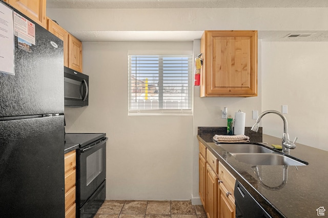 kitchen with black appliances, a sink, light brown cabinetry, dark stone countertops, and baseboards