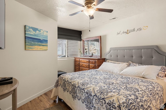 bedroom featuring wood finished floors, a textured ceiling, baseboards, and a ceiling fan