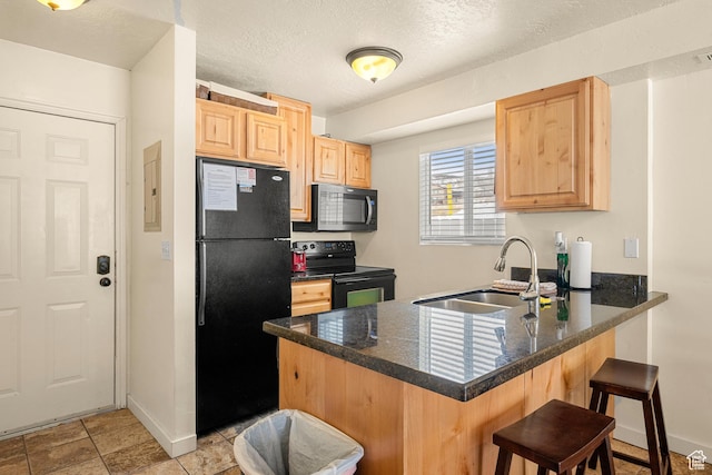 kitchen with black appliances, light brown cabinets, a sink, a peninsula, and a kitchen breakfast bar