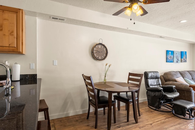 dining room with a textured ceiling, light wood-style floors, a ceiling fan, baseboards, and recessed lighting