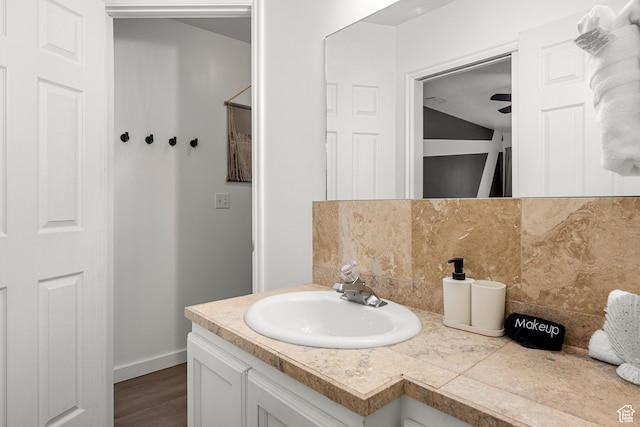bathroom with decorative backsplash, vanity, wood finished floors, and baseboards