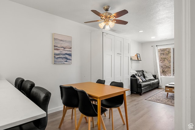 dining area with a ceiling fan, light wood-type flooring, baseboards, recessed lighting, and a textured ceiling