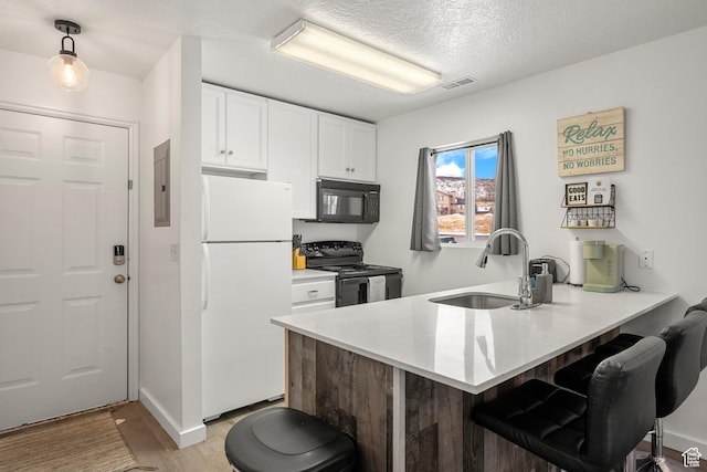 kitchen with black appliances, a sink, a breakfast bar, a peninsula, and a textured ceiling