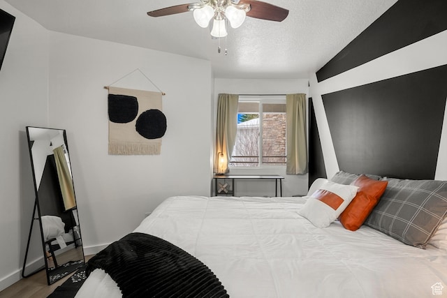 bedroom featuring wood finished floors, a textured ceiling, a ceiling fan, and lofted ceiling