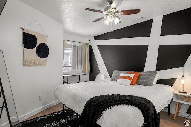 bedroom with wood finished floors, vaulted ceiling, baseboards, and ceiling fan