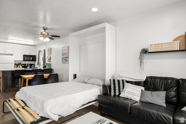 bedroom featuring freestanding refrigerator, wood finished floors, a textured ceiling, a ceiling fan, and recessed lighting