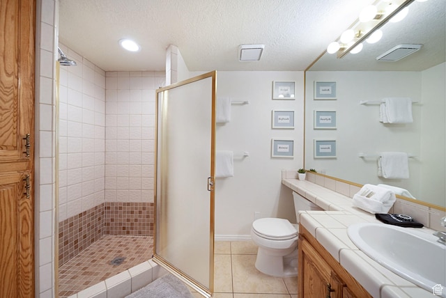 bathroom featuring tile patterned floors, toilet, a shower with shower door, a textured ceiling, and vanity