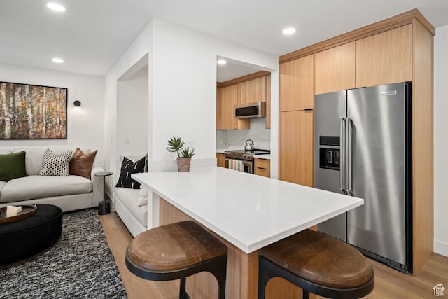 401 Silver King Dr, Park City, UT 84060 - kitchen featuring stainless steel appliances, a kitchen breakfast bar, tasteful backsplash, light hardwood / wood-style flooring, and kitchen peninsula