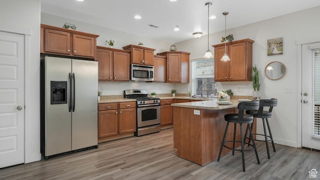 1026 N Shepard Creek Pkwy Unit 4, Farmington, UT 84025 - kitchen with a kitchen bar, kitchen peninsula, light wood-type flooring, stainless steel appliances, and pendant lighting