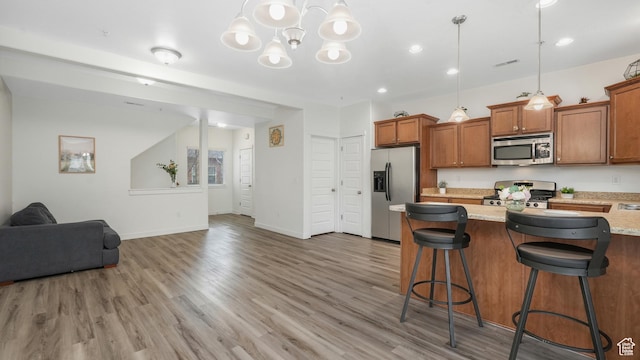 1026 N Shepard Creek Pkwy Unit 4, Farmington, UT 84025 - kitchen featuring light stone counters, decorative light fixtures, a breakfast bar, appliances with stainless steel finishes, and hardwood / wood-style flooring