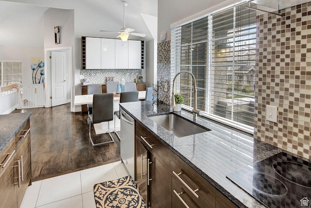 kitchen featuring dishwasher, sink, dark wood-type flooring, dark stone countertops, and white cabinets