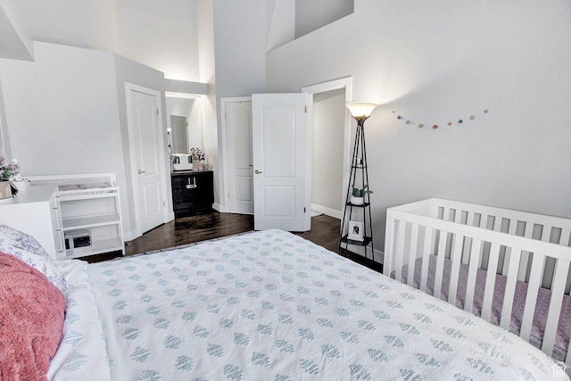 bedroom featuring a high ceiling, dark hardwood / wood-style flooring, and a nursery area