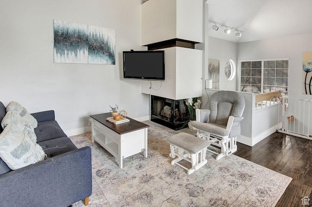 living room with a multi sided fireplace, track lighting, and hardwood / wood-style flooring