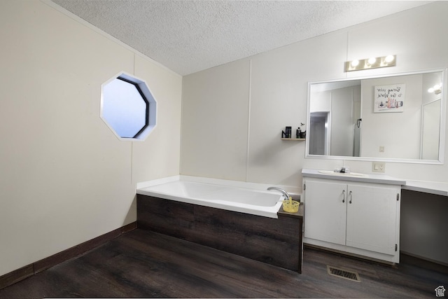 bathroom with hardwood / wood-style flooring, vanity, a bathtub, and a textured ceiling
