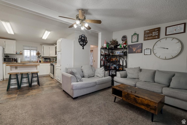 living room with dark colored carpet, ceiling fan, sink, and a textured ceiling