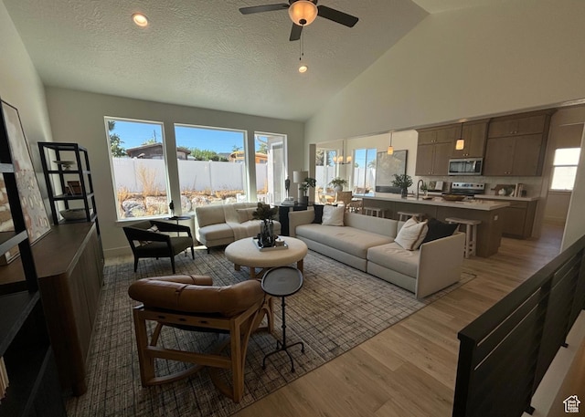 living room with ceiling fan, light hardwood / wood-style floors, a textured ceiling, and sink