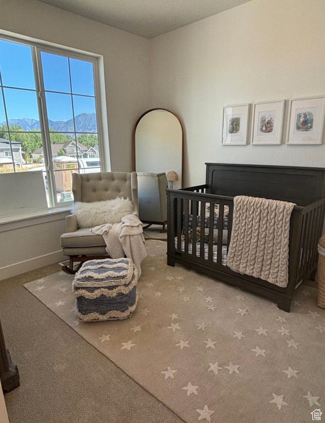 carpeted bedroom featuring a crib and a mountain view