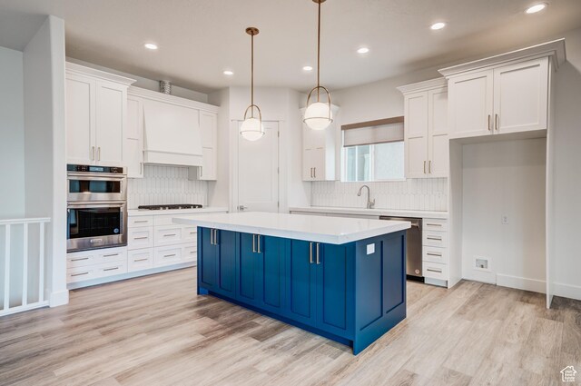 1259 W Moon Way Unit 134, Riverton, UT 84065 - kitchen with a center island, stainless steel appliances, light hardwood / wood-style floors, decorative light fixtures, and white cabinets
