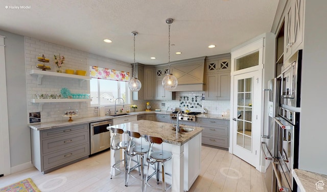 1165 N 360 E Unit 75, Salem, UT 84653 - kitchen featuring gray cabinets, appliances with stainless steel finishes, a kitchen breakfast bar, light stone countertops, and a center island with sink