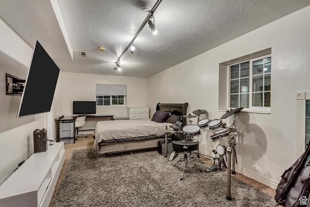 bedroom with carpet, a textured ceiling, track lighting, and baseboards