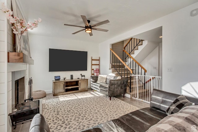 living area with a ceiling fan, stairway, a fireplace, and baseboards