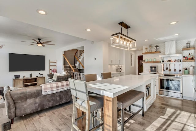 dining room with light wood-style flooring, stairway, ceiling fan, recessed lighting, and a chandelier