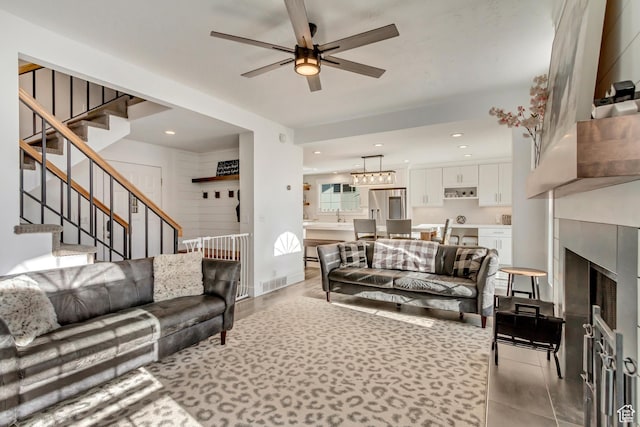 living area with a ceiling fan, stairway, a fireplace, recessed lighting, and light tile patterned floors